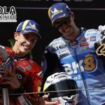 Marc Marquez dan Alex Marquez merayakan kemenangan di podium MotoGP Catalunya 2025 sambil mengangkat trofi juara, disorot oleh Bolaterkini88.